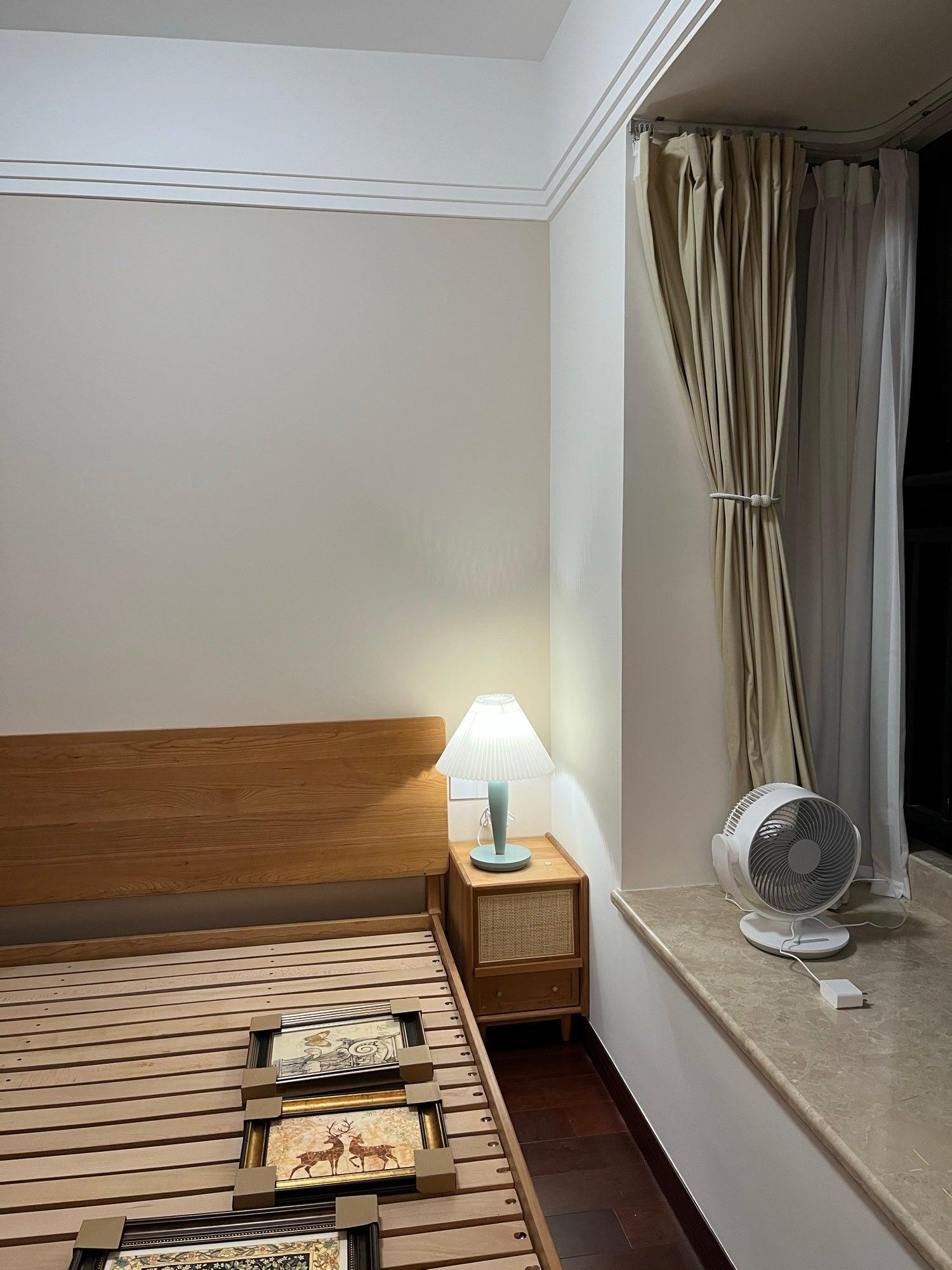 Light-blue bedside lamp by curtained window