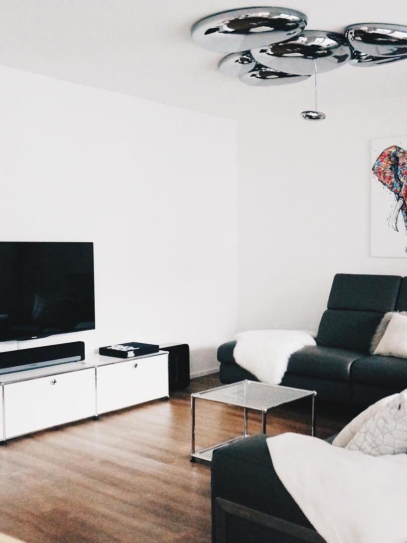 Reflective ceiling cluster above TV cabinet and black armchairs