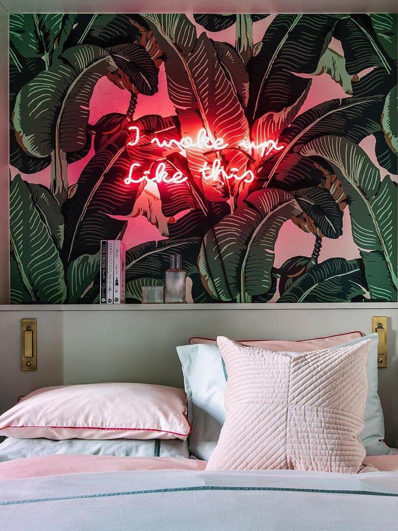 Recessed lights beside a bed beneath patterned wallpaper