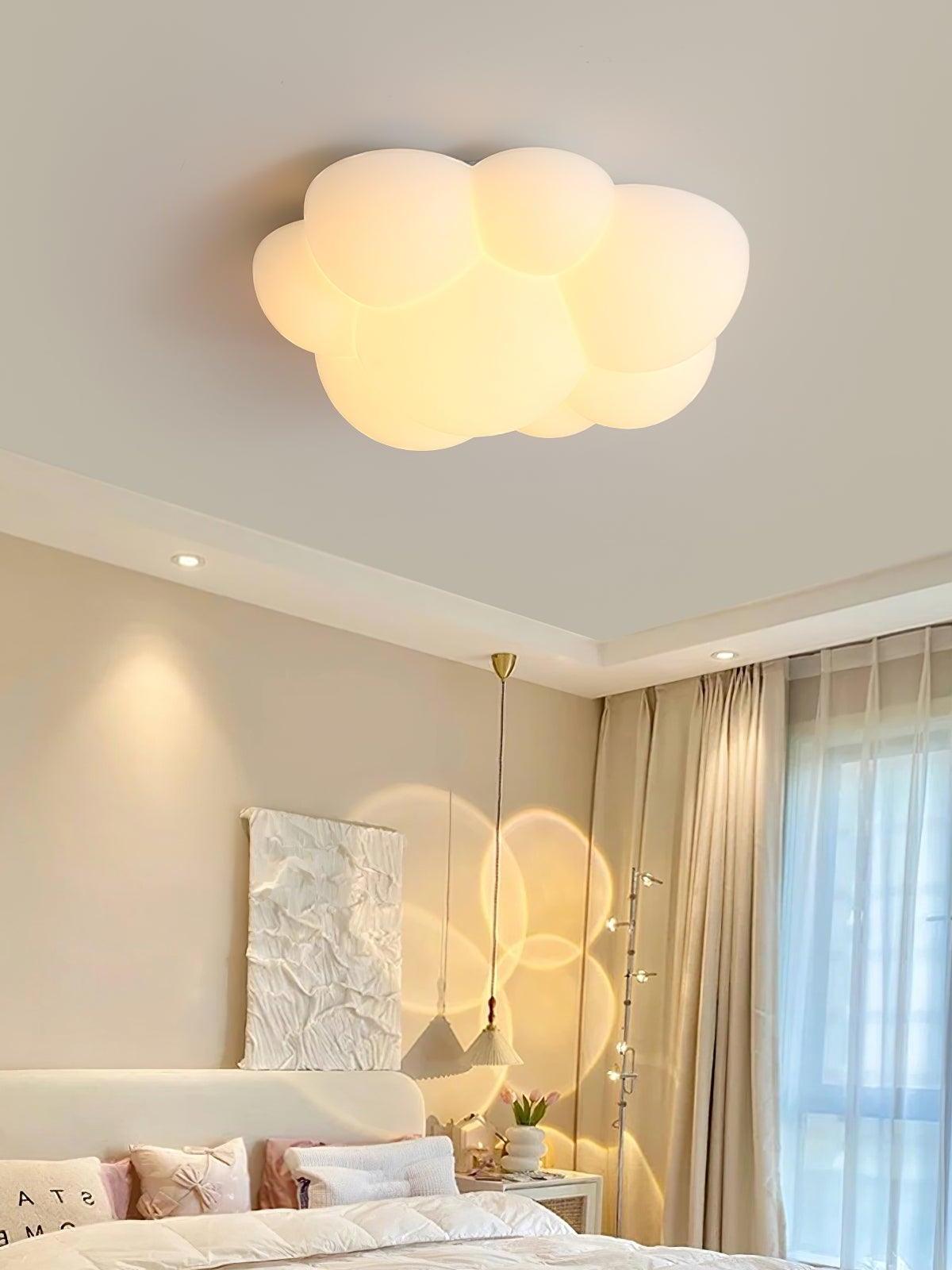 Illuminated Nuage cloud ceiling light above a bed with tall upholstered panels