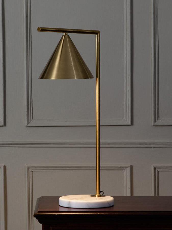 Lit gold-tone cone lamp against a panelled wall
