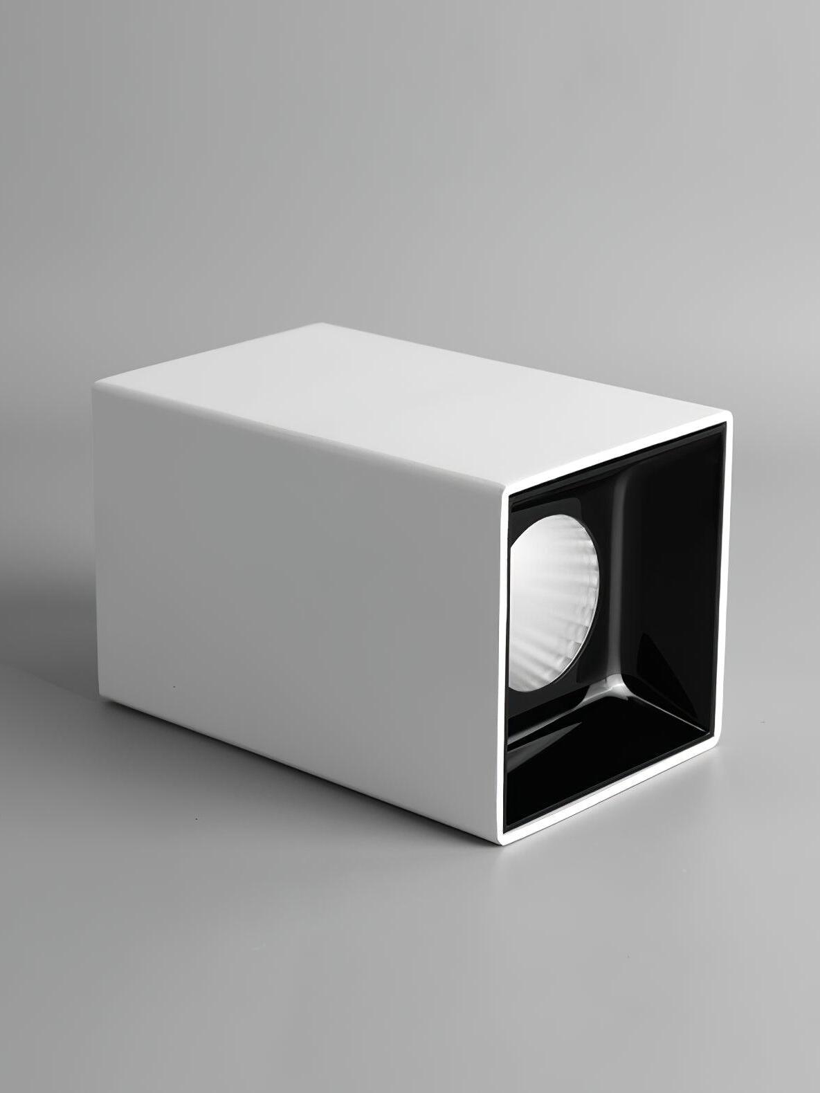 White metal spotlight lying on its side, with a round reflector inside a glossy black square recess