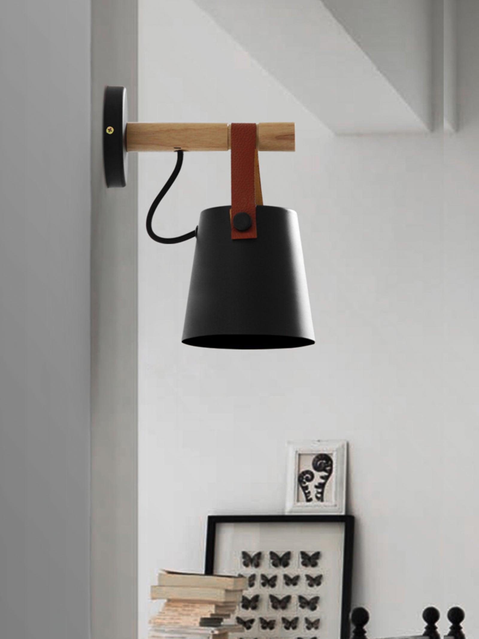Black wood-arm wall lamp on a pale interior wall