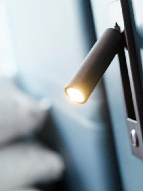 Illuminated cylindrical reading head beside a bed