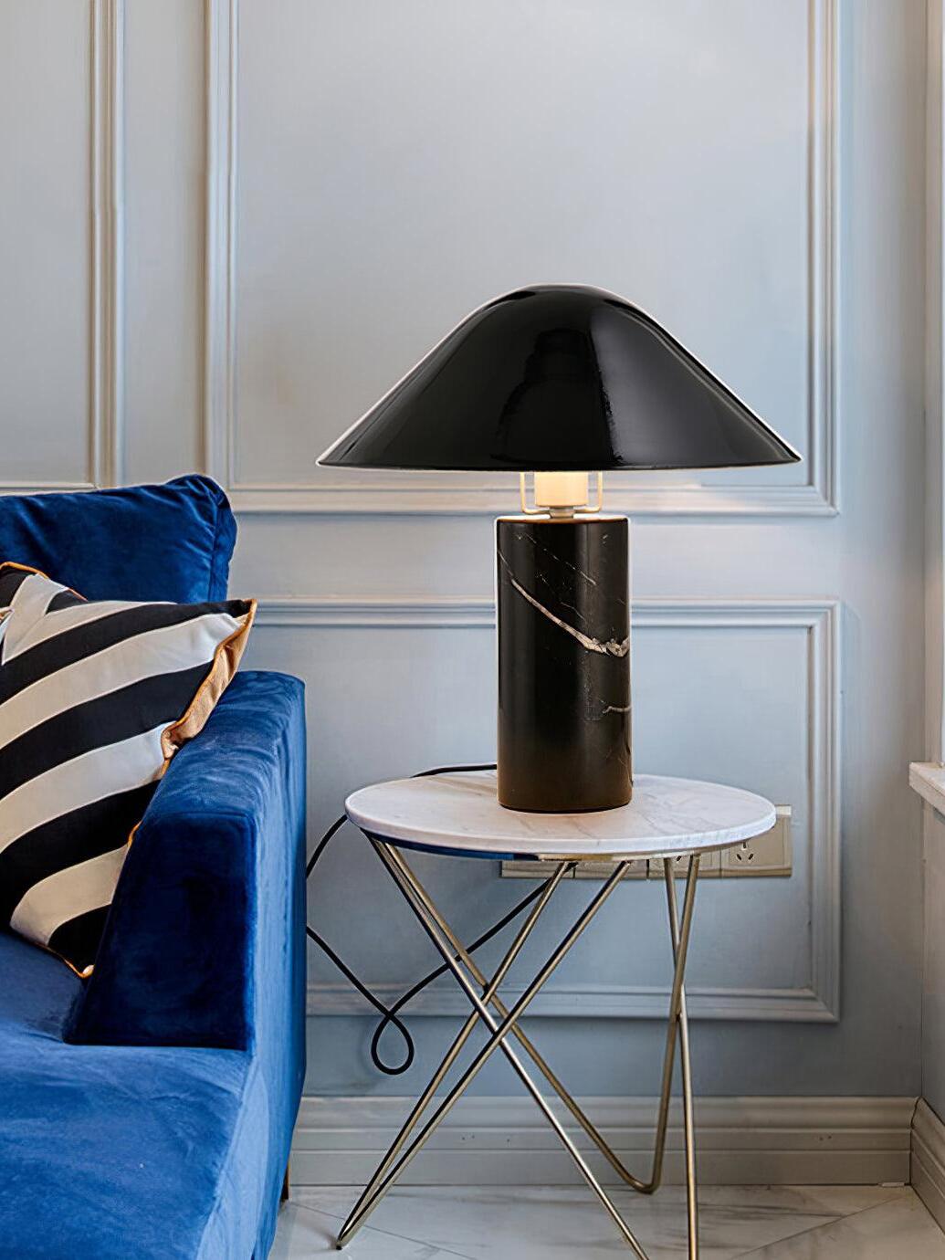 Black marble lamp on round table beside blue sofa