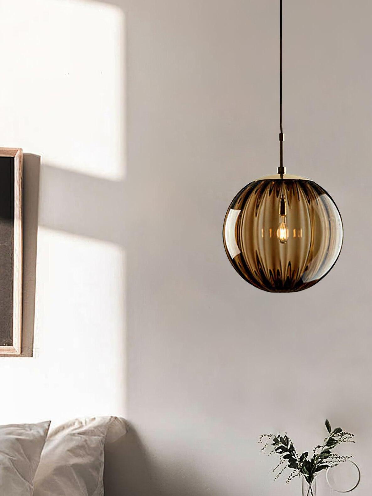 Light brown fluted globe pendant beside pale cushions and a vase