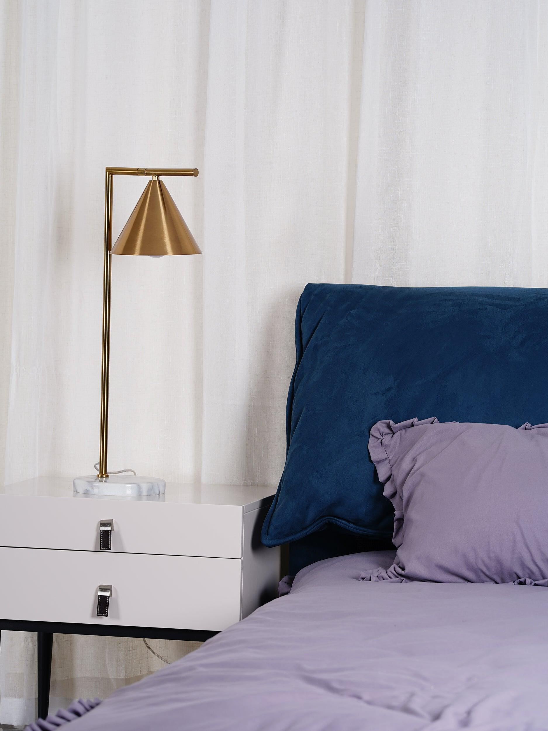 Wider bedroom view with cone table lamp and blue headboard