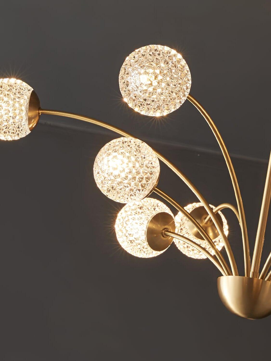 Close view of glowing textured glass globes on curved brass-tone arms beside a partial bowl-shaped hub
