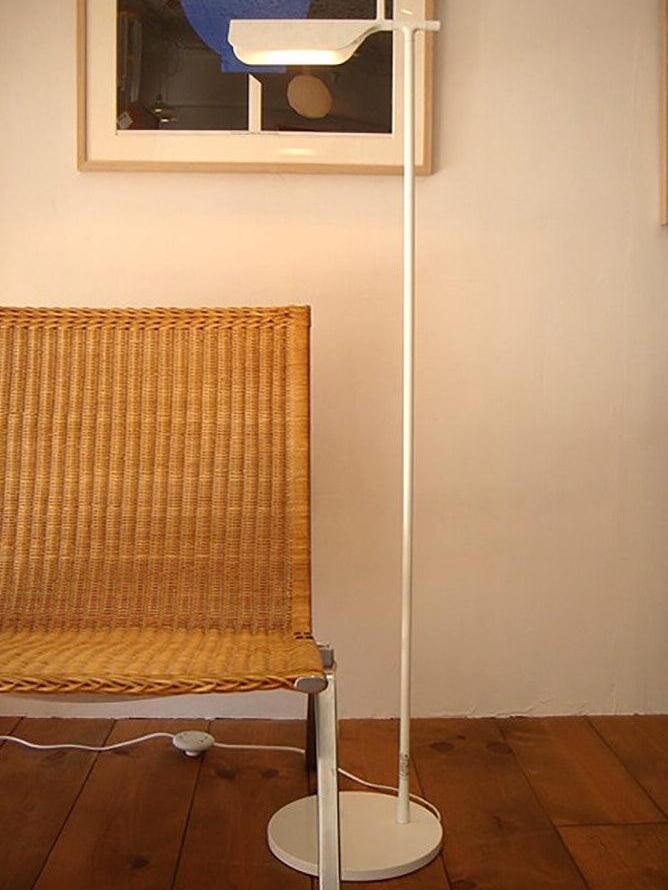 White floor lamp beside a woven chair