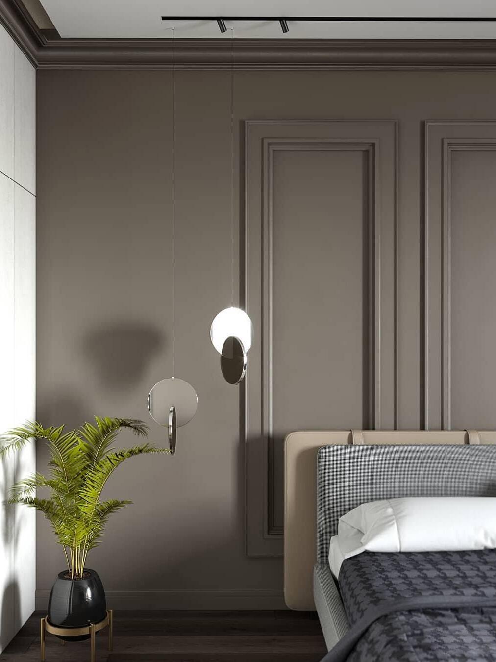 Two reflective disc pendants beside an upholstered bed, grey wall and plant
