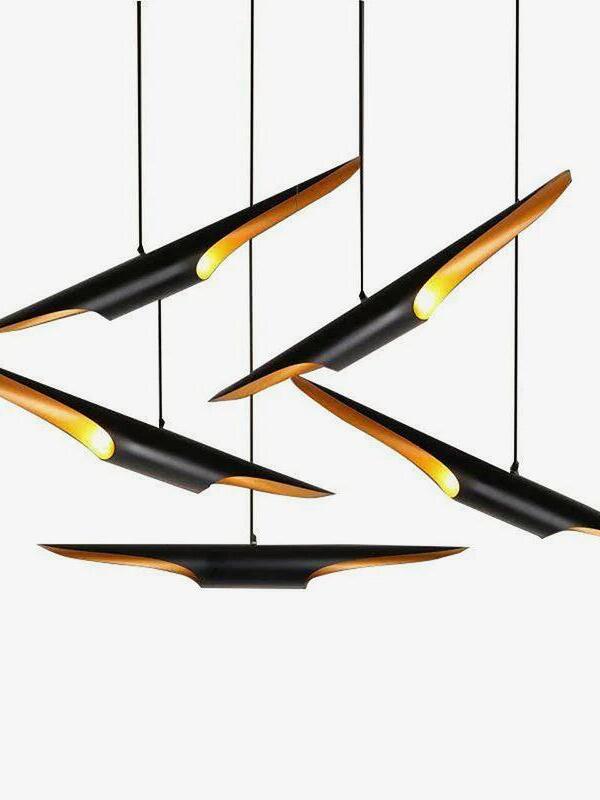 Five separate black and gold pipe pendants hanging at different angles against a white background