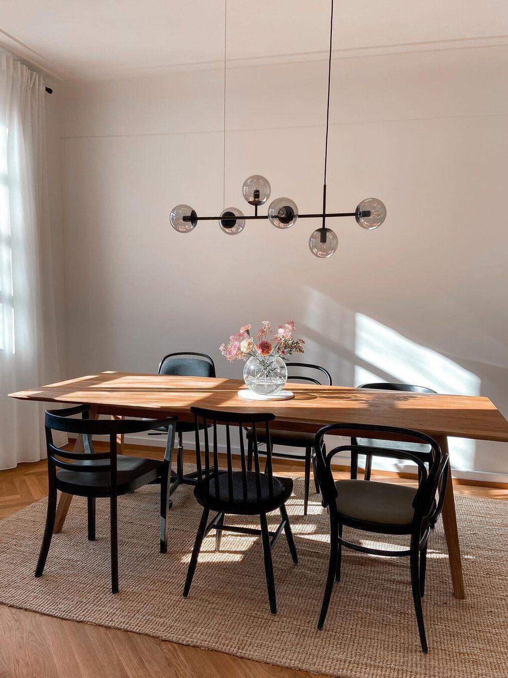 Black globe chandelier over a wood dining table