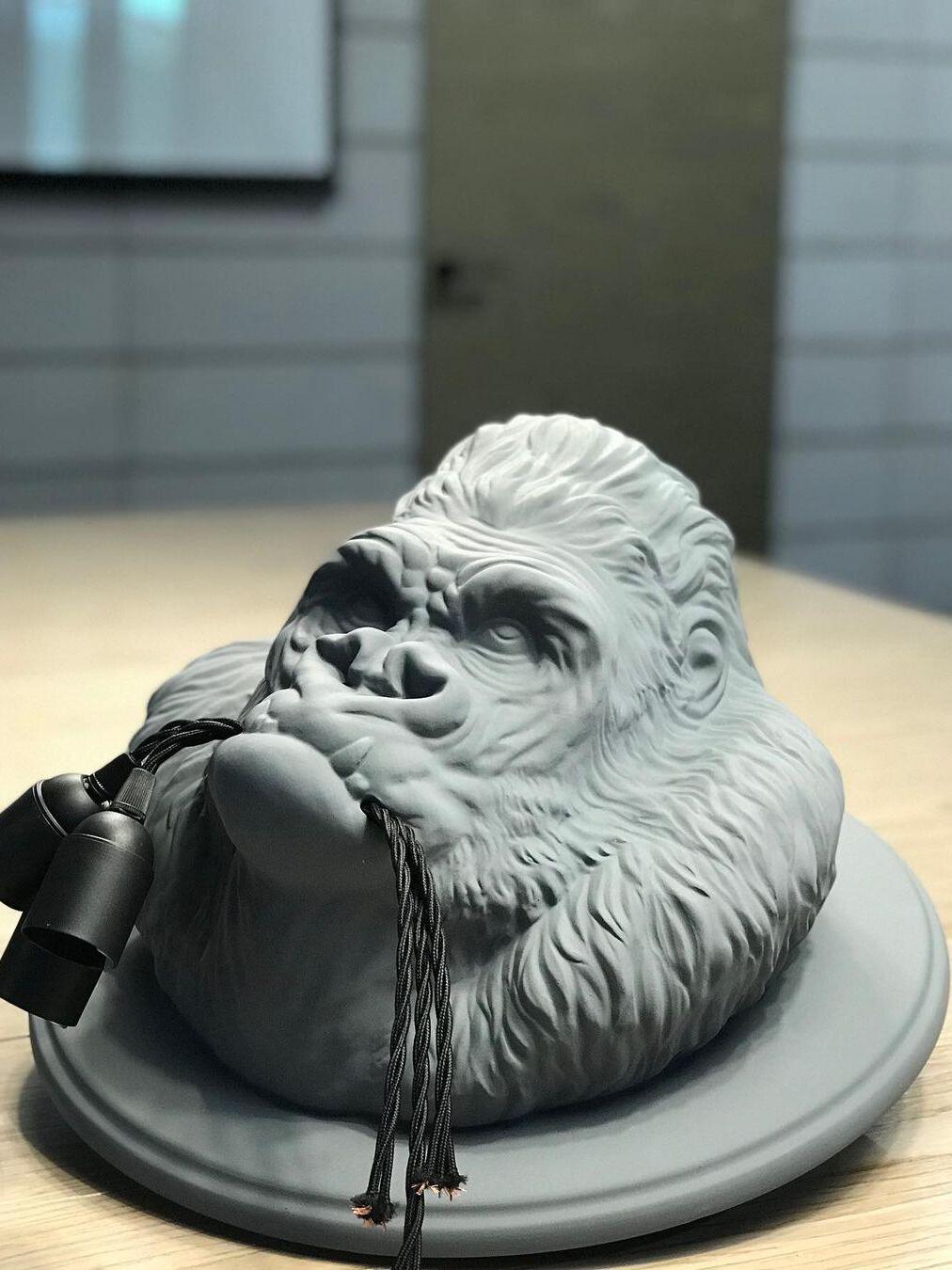 Close grey gorilla head on round backing laid on tabletop near book