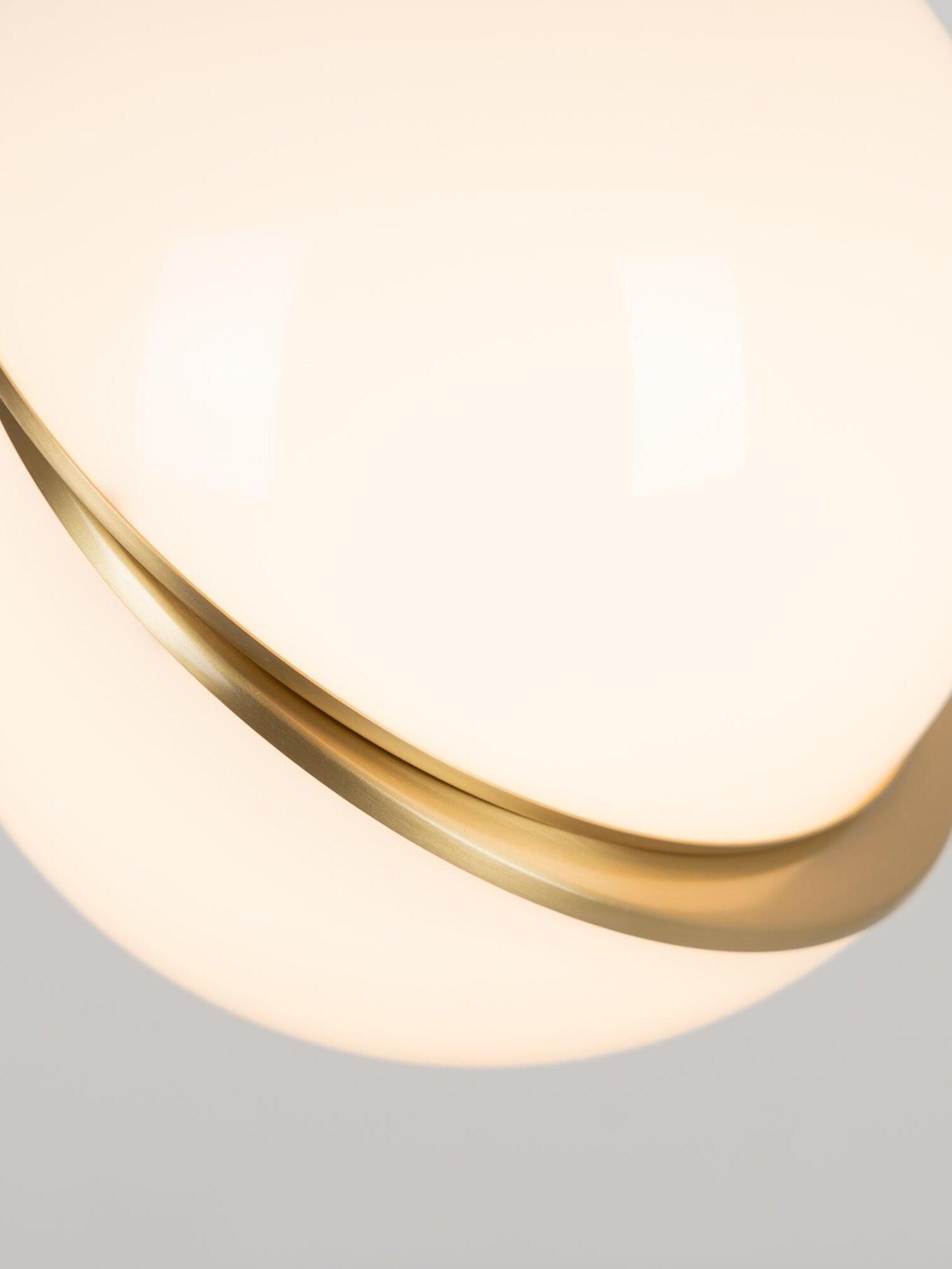 Tight lit detail of Crescent offset white globe halves and the curved gold-colour crescent band