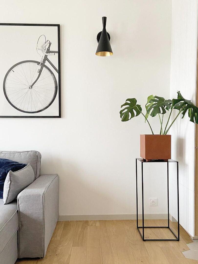 Black conical wall sconce above sofa in bright living room