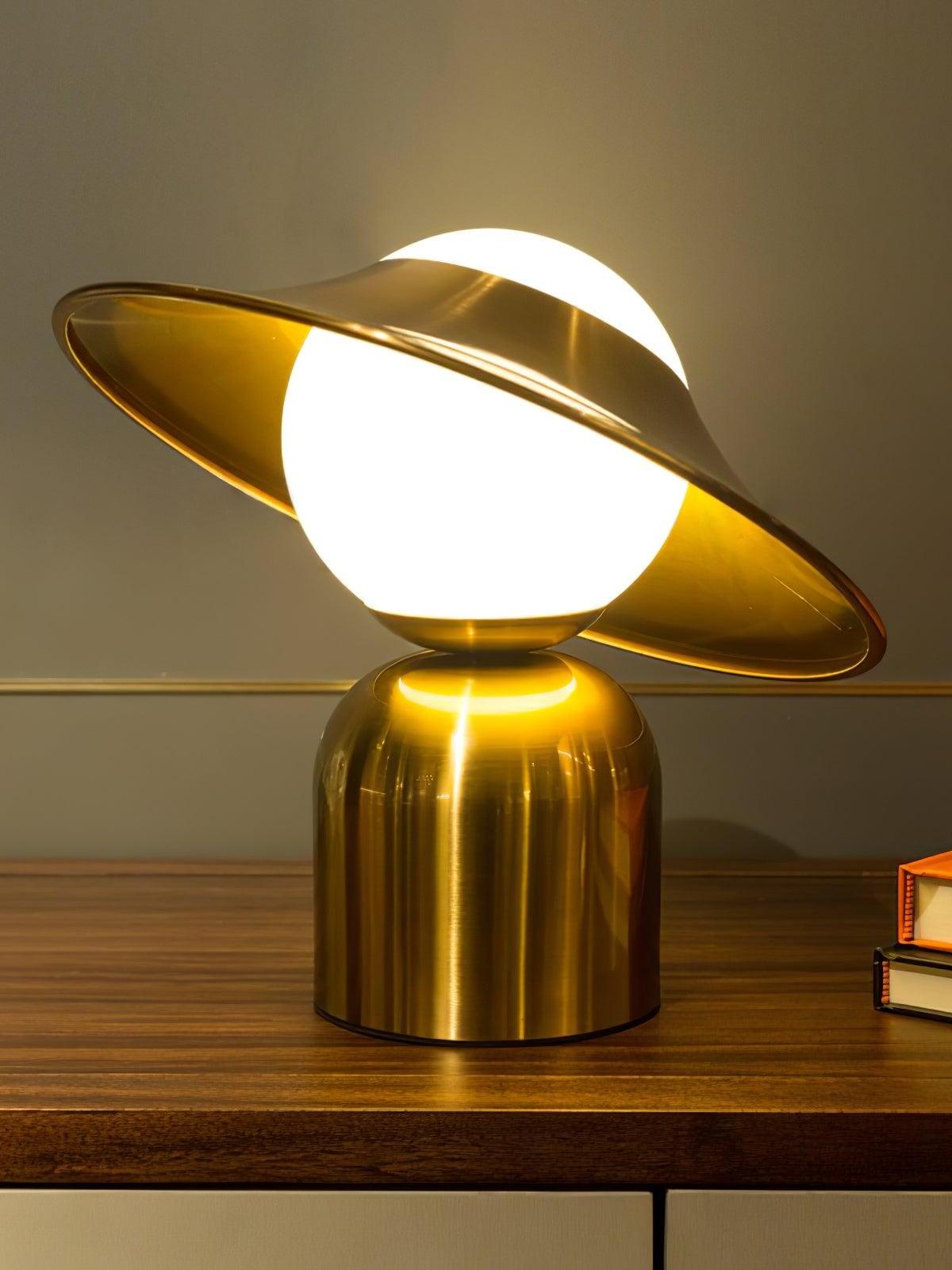 Gold disc table lamp glowing on dark wood