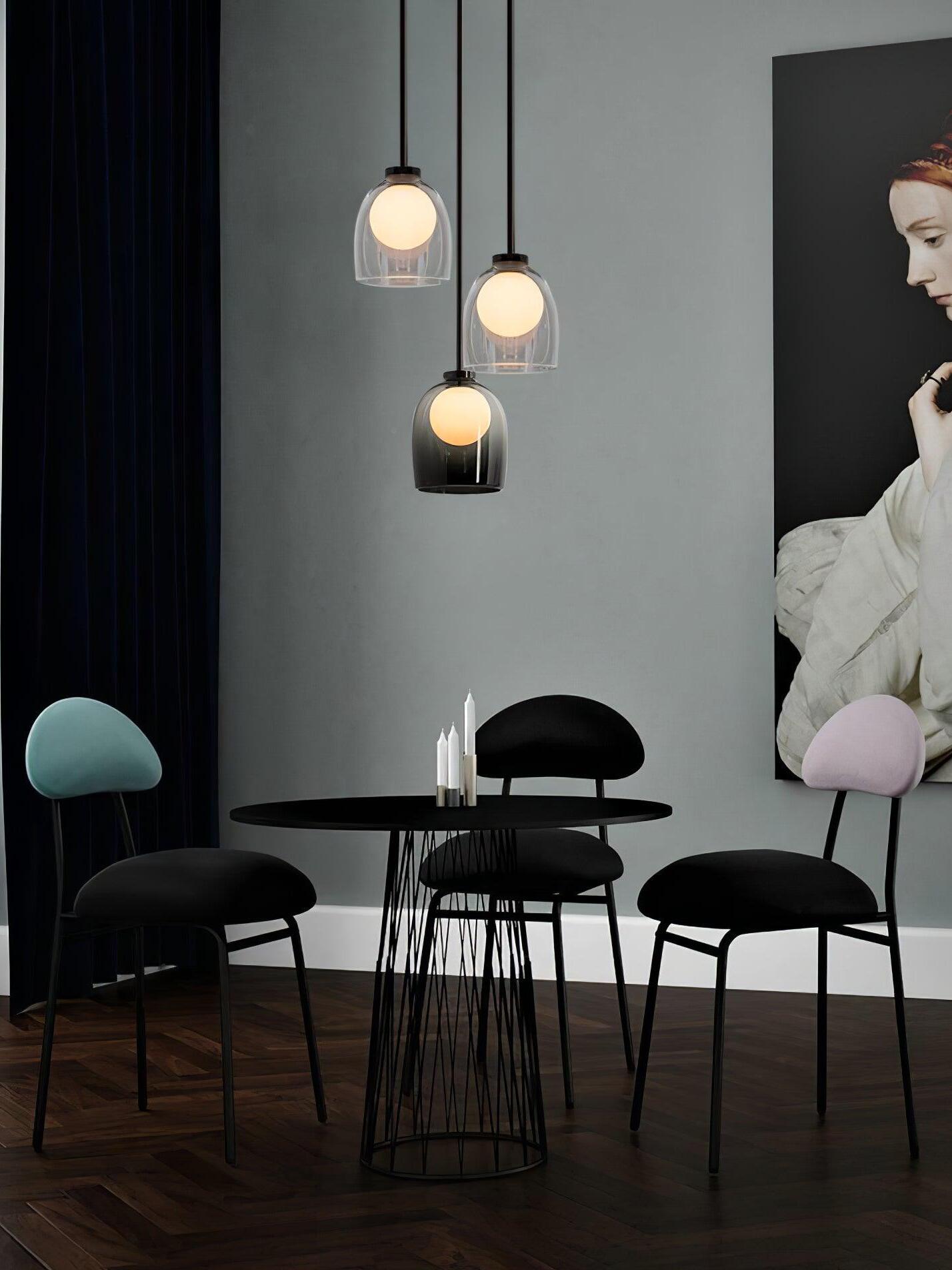 Clear and gradient-black Crux pendants grouped above a round dining table