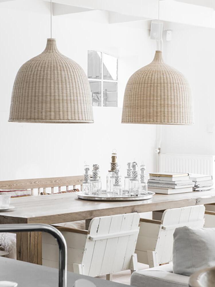 Two woven bell pendants above a dining table