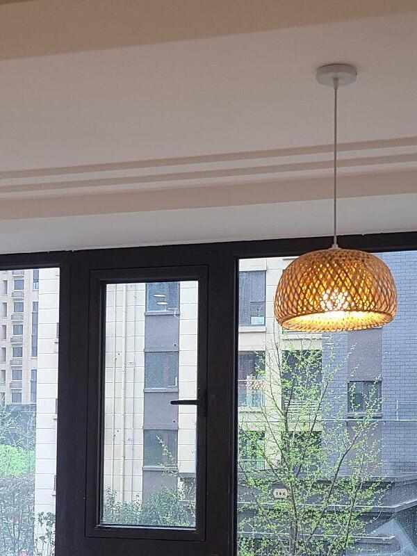 Single woven bamboo pendant before dark-framed window