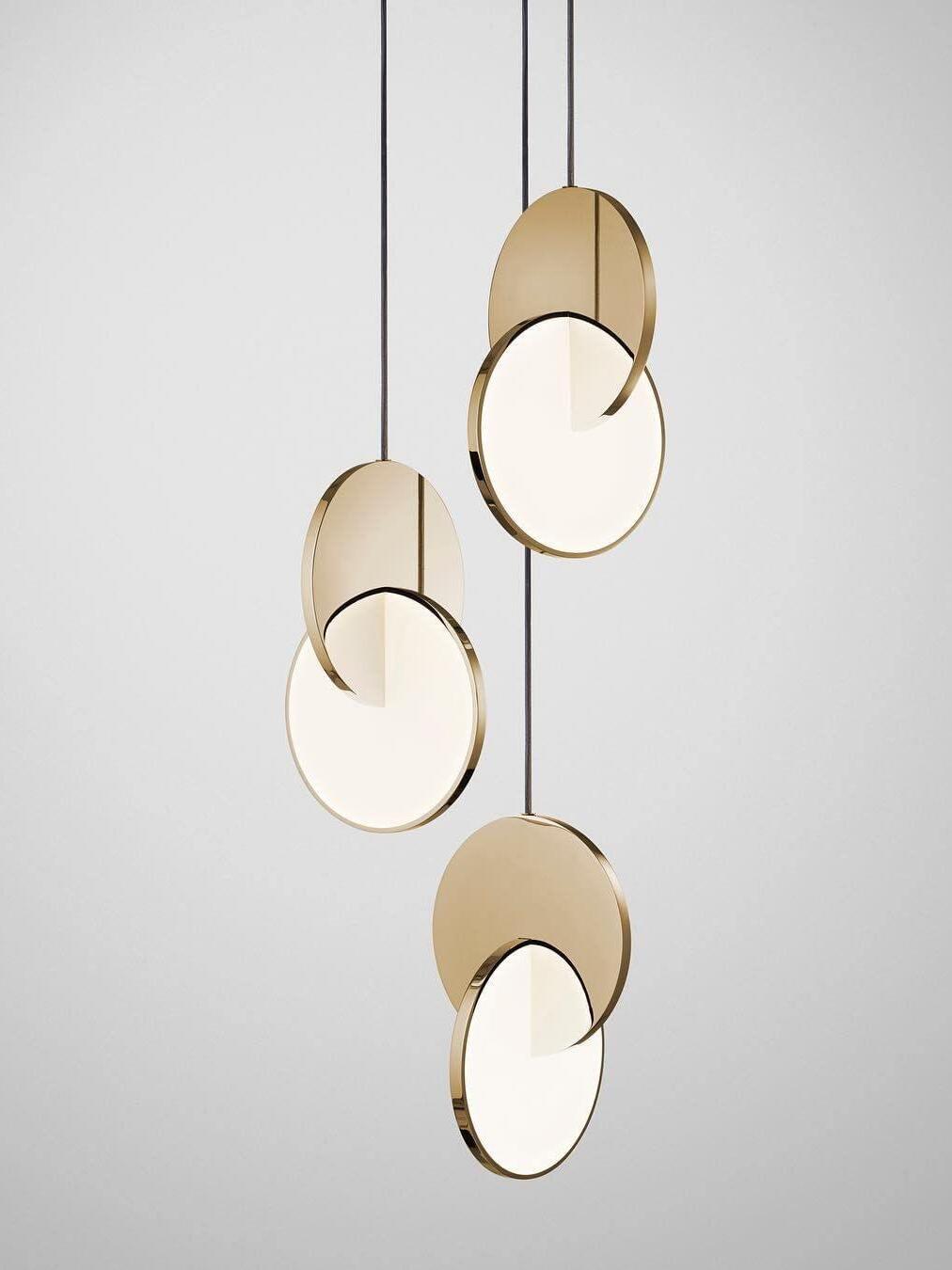 Three gold disc pendant lights at staggered drops against white
