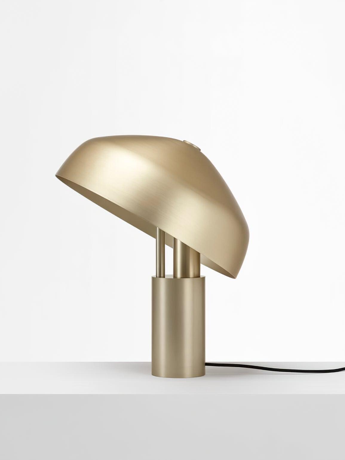 Gold tipped dome lamp with cord on white surface