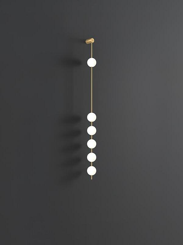 Six-globe gold-colour wall lamp with one upper globe and five lower globes against dark grey