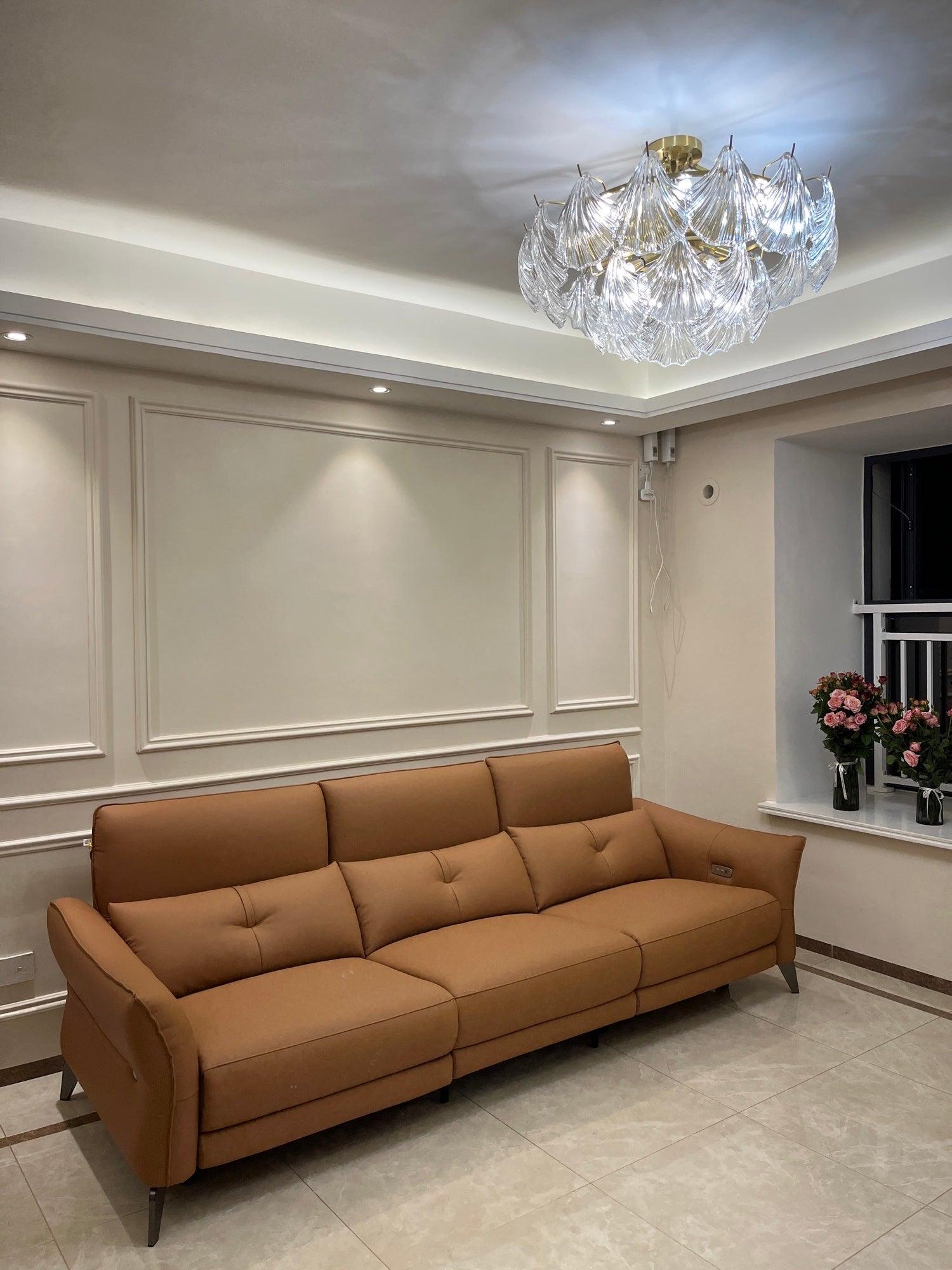 Round ribbed glass light casting patterns on a white paneled ceiling above a brown sofa