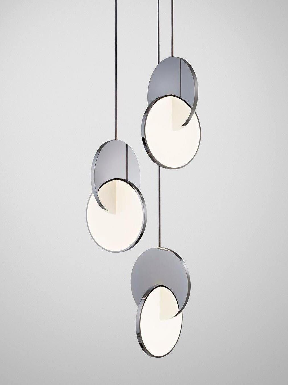 Three chrome disc pendant lights with separate cords at staggered drops against white