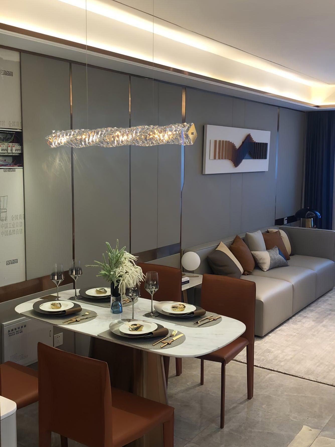 Crystal pendant over a dining table beside a brown sofa in an open living and dining room