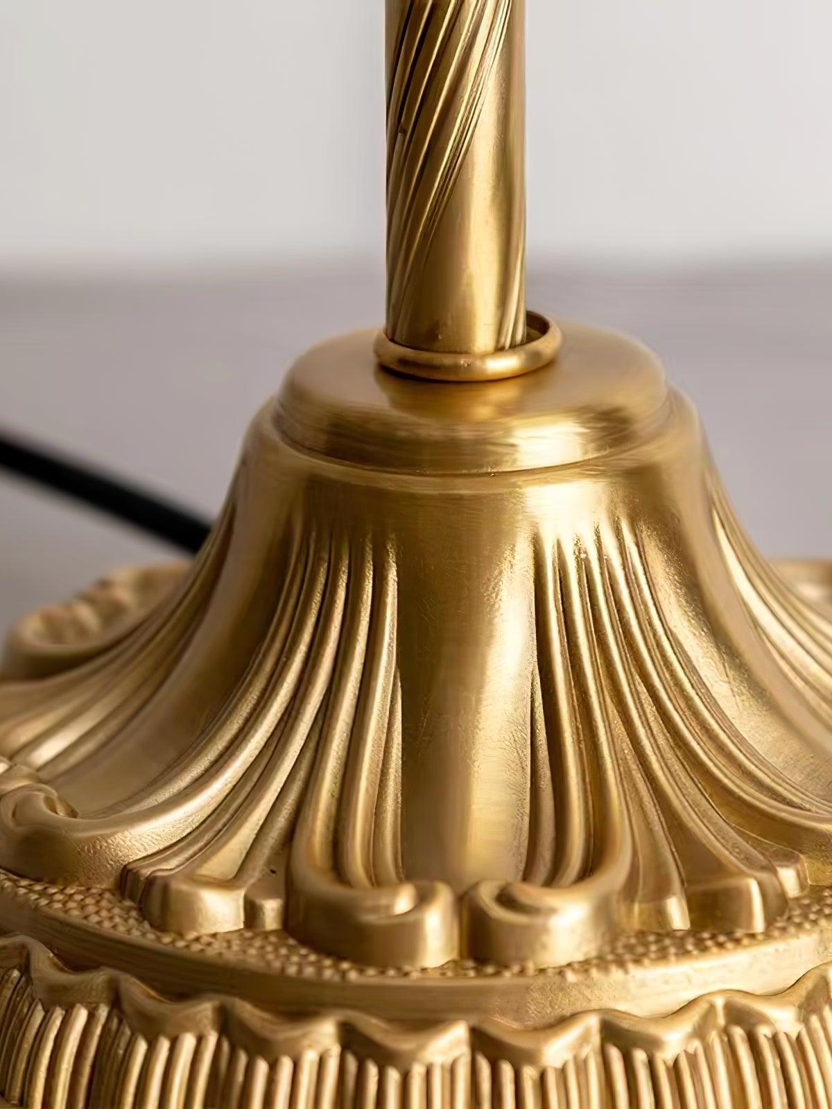 Close-up of the twisted-look stem and fluted gold-tone pedestal base of the crystal table lamp.