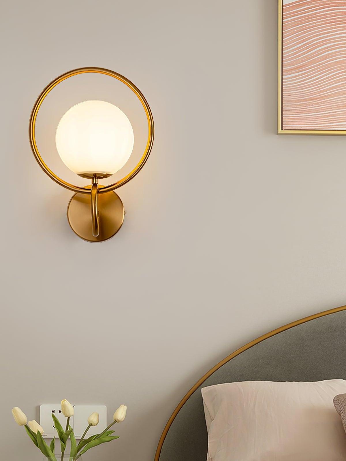 Glowing white globe within gold oval ring beside bed