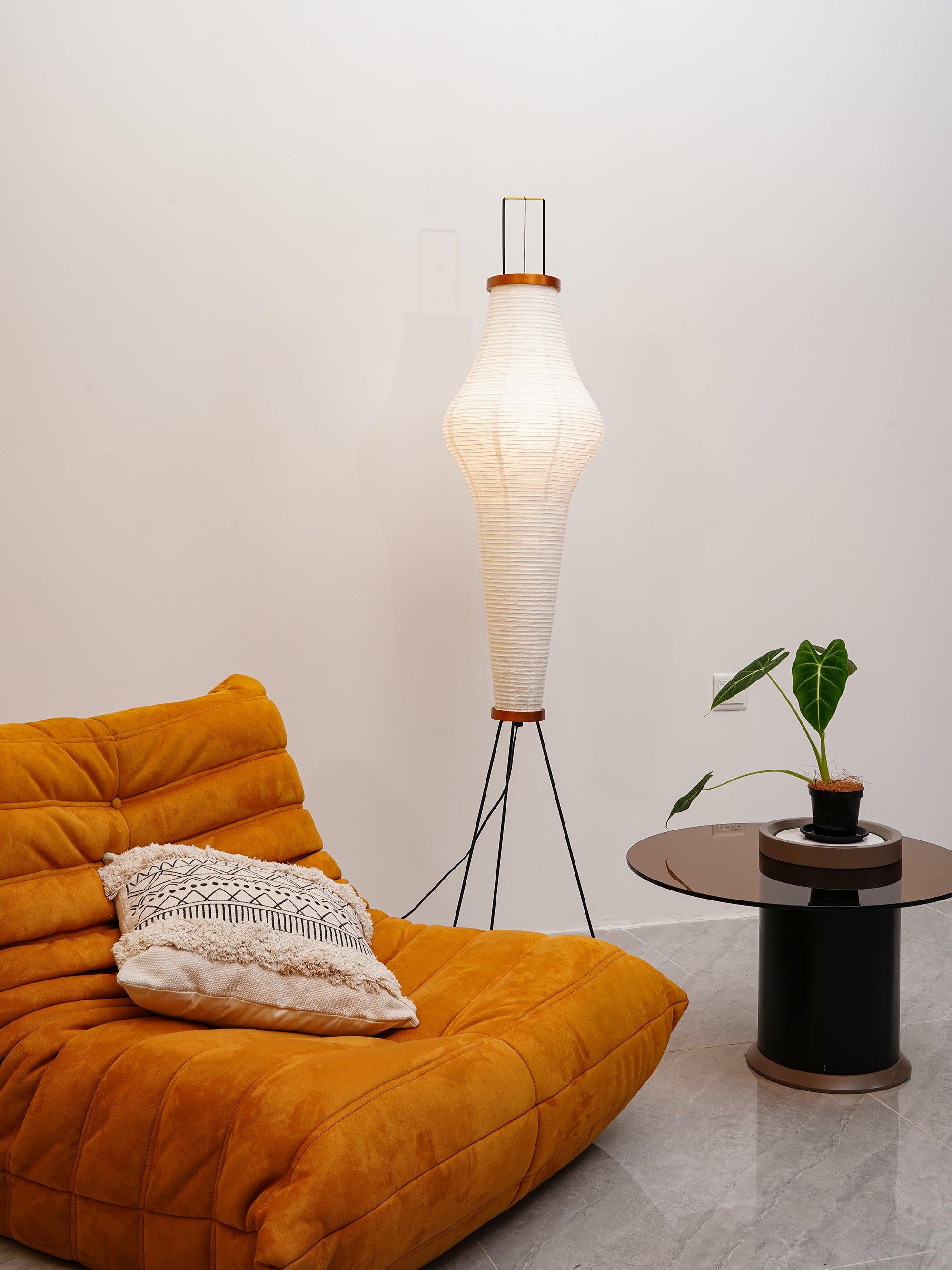 Tall shaped paper floor lamp beside orange sofa