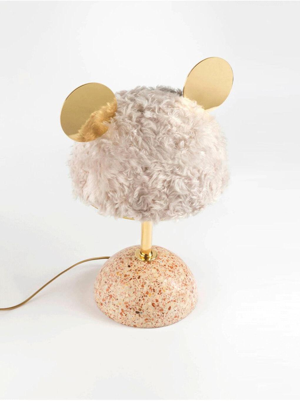 Pale plush lamp with warm-speckled base and cord trailing to the left
