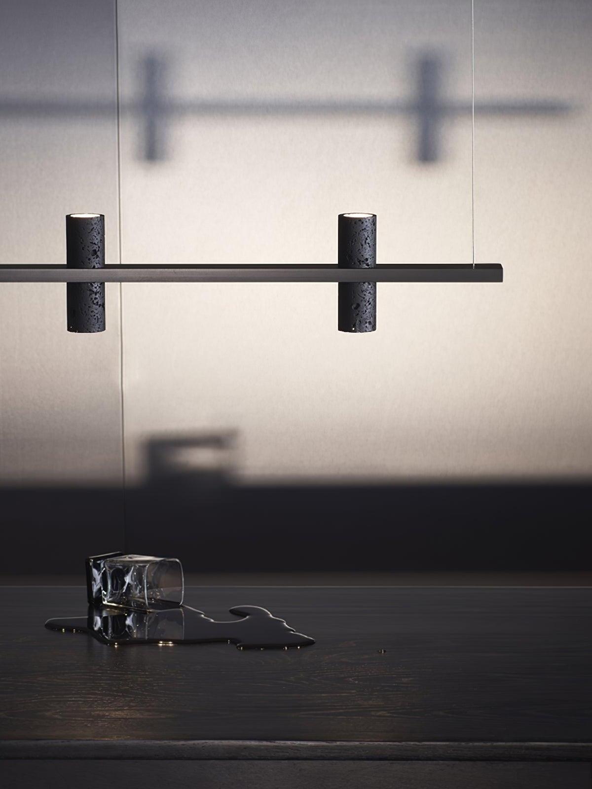 Linear black fixture casting cylindrical shadows on a wall