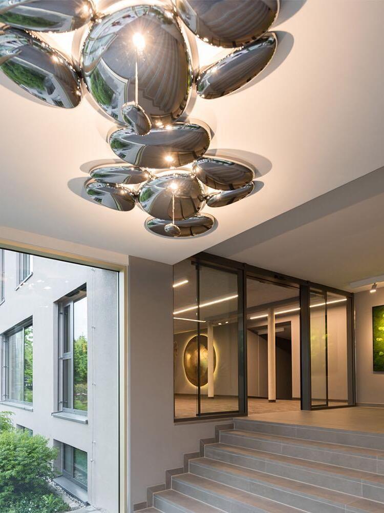 Large grouped reflective pebble installation above stairs and entry space