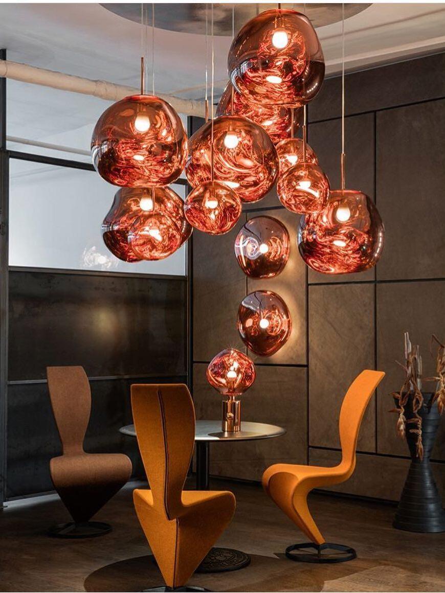 Red-orange pendant group above sculptural chairs