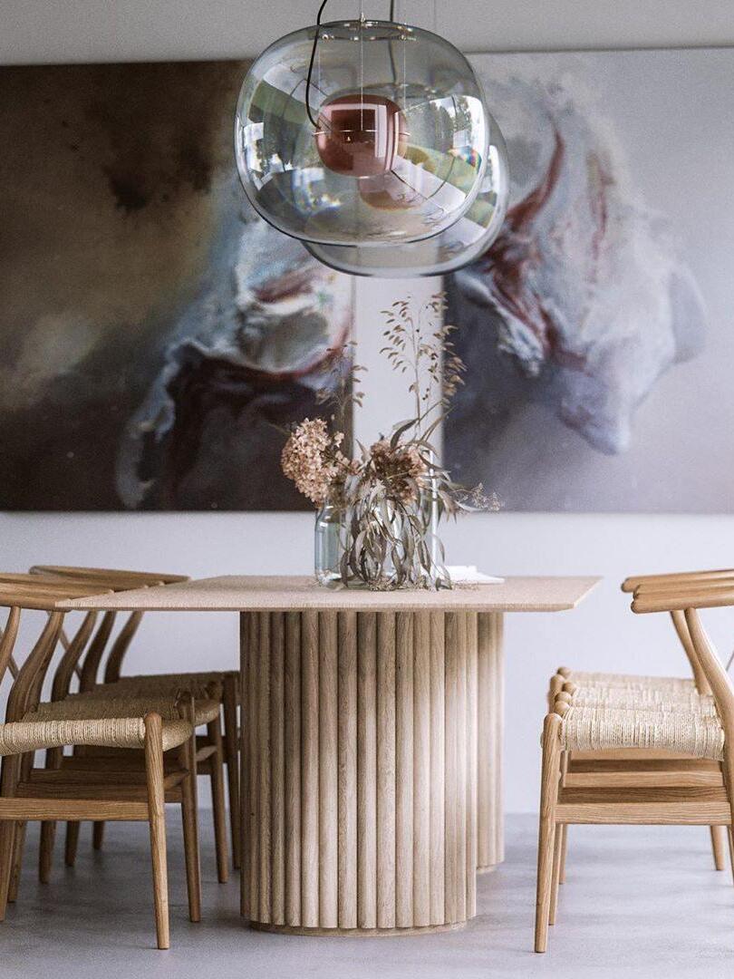 Glass pendant above a pale wooden dining table beneath large artwork