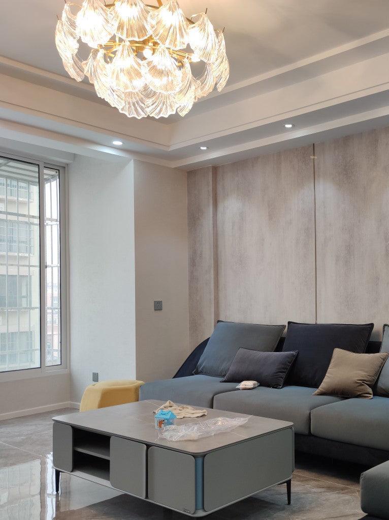 Shell-panel ceiling light above a gray sofa and square coffee tables near a window