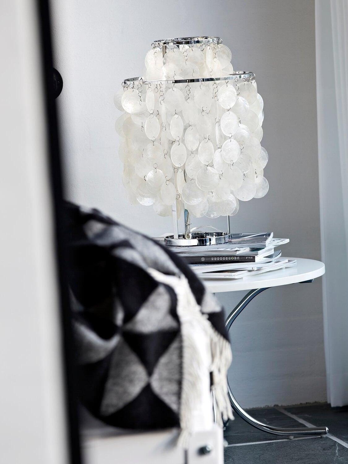 Shell table lamp on books beside sofa and round table