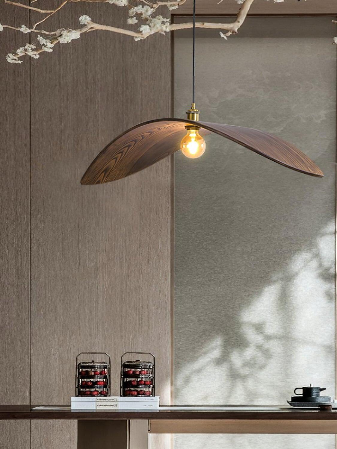 Curve wooden pendant above a narrow counter with books and light falling across a textured wall