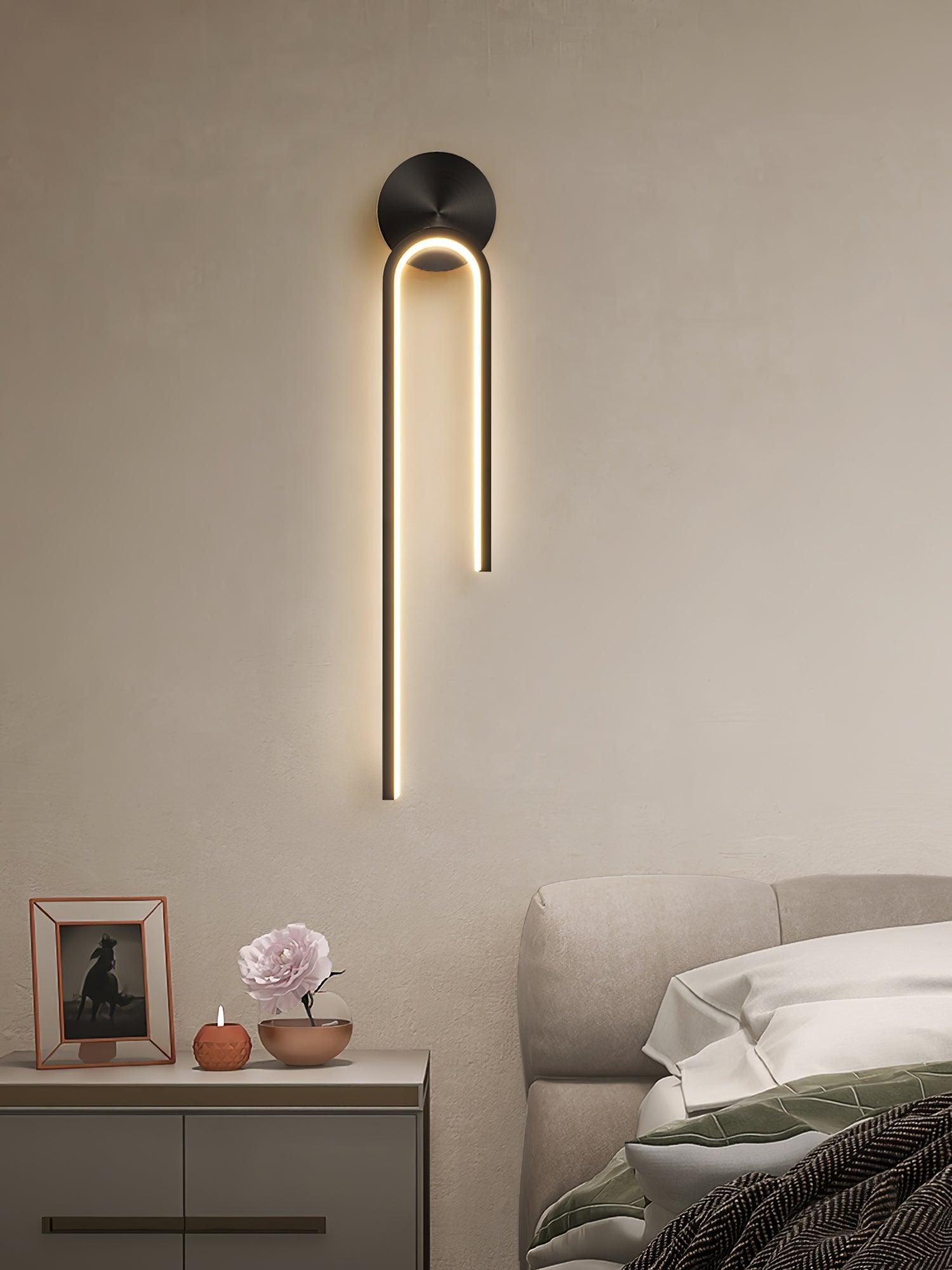 Glowing black arch with a long left arm above a bedside photograph, flower and candle