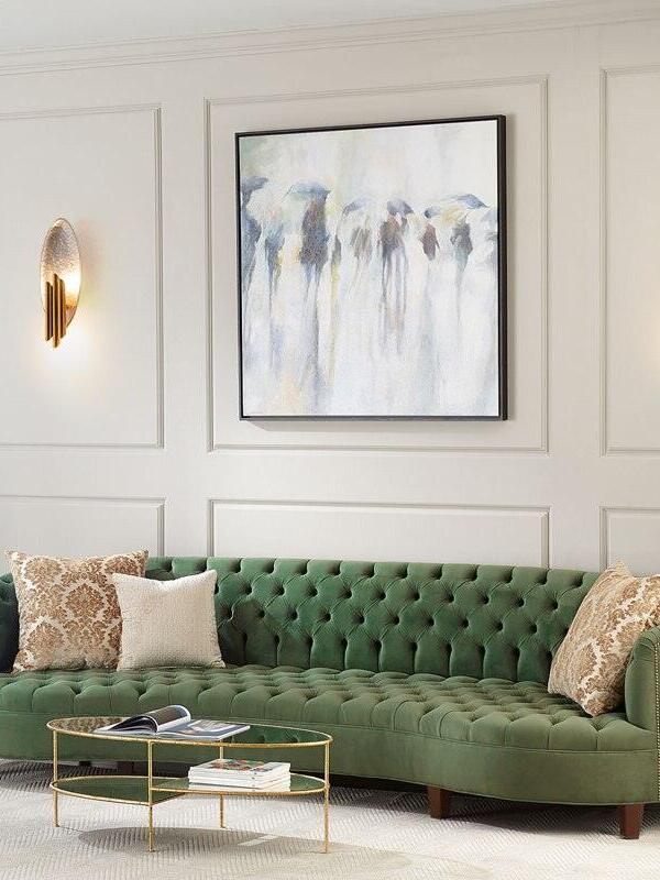 Small oval wall light above green sofa beside framed painting