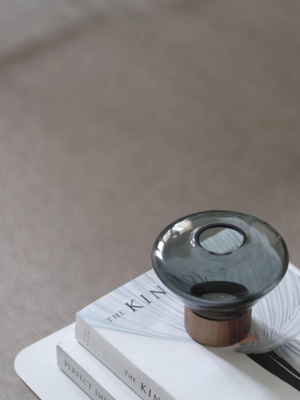Small smoky rounded glass lamp with top opening on books on side table