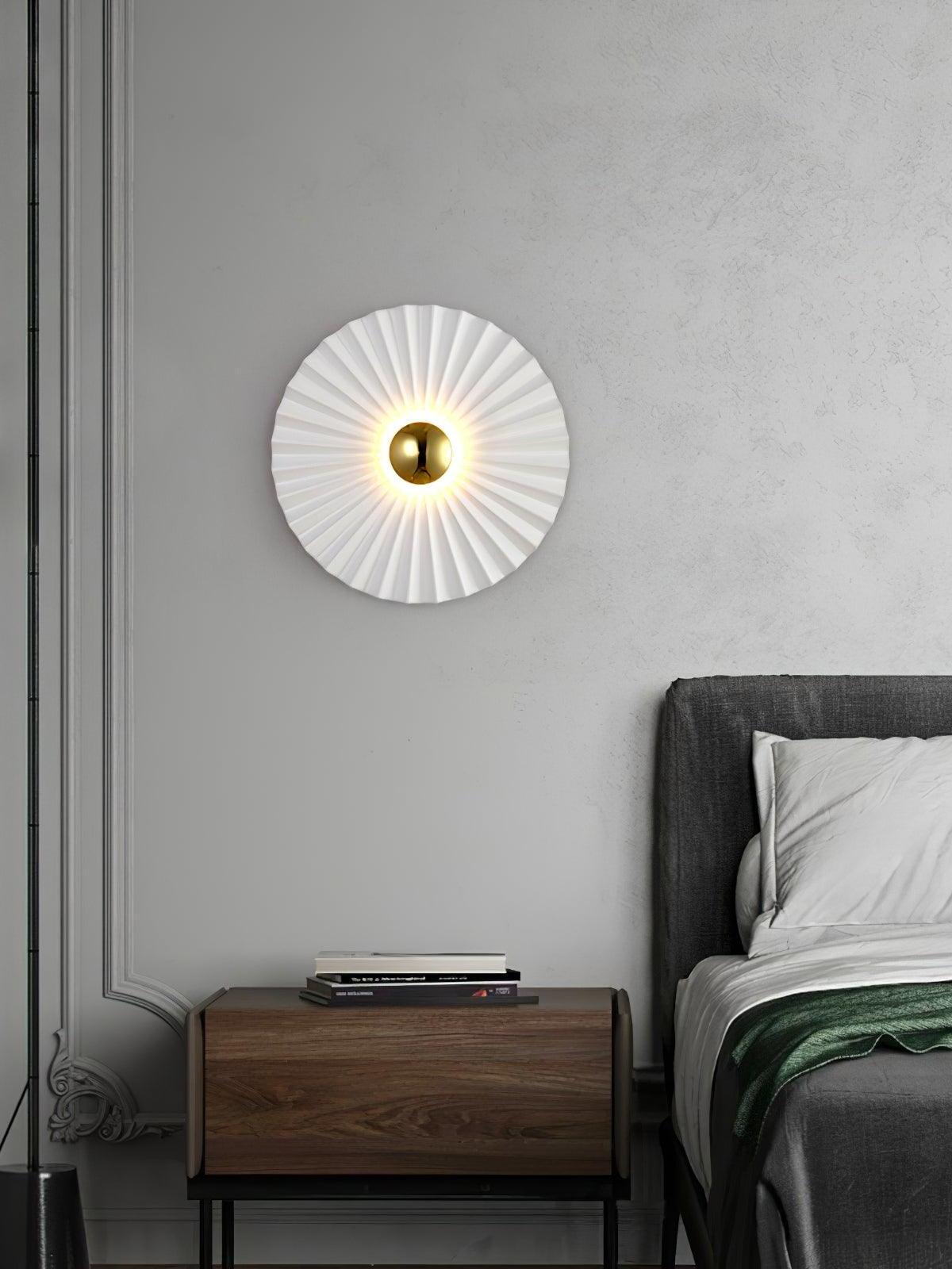 Pleated wall lamp mounted beside a bed