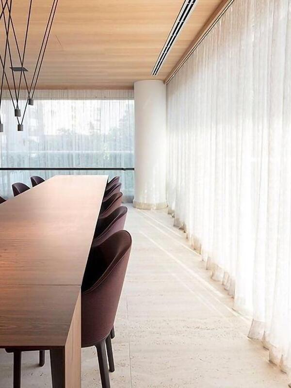 Partial black rod-and-light arrangement above a long table with burgundy chairs beside sheer curtains