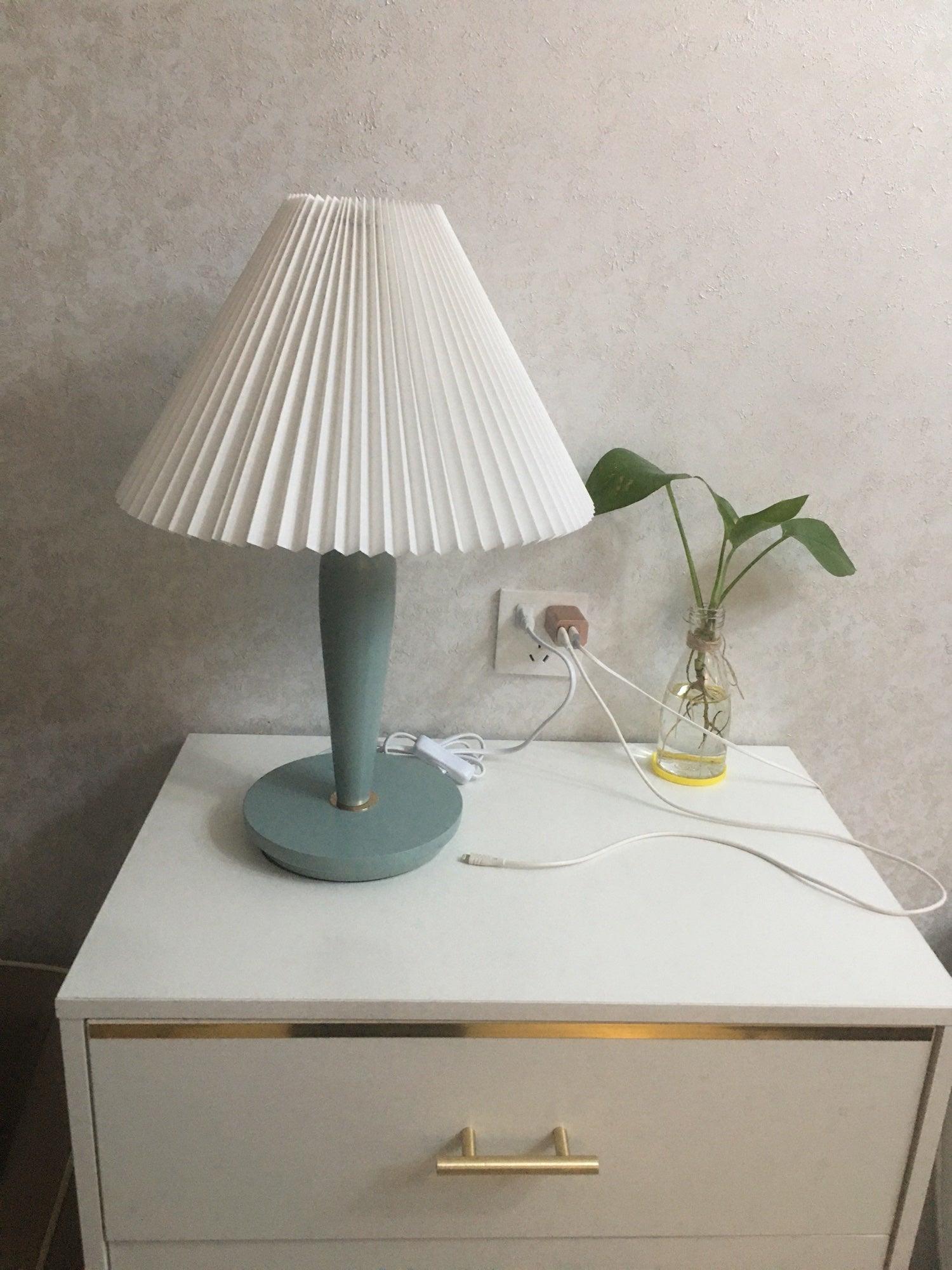 Light-blue table lamp on white cabinet with cord visible