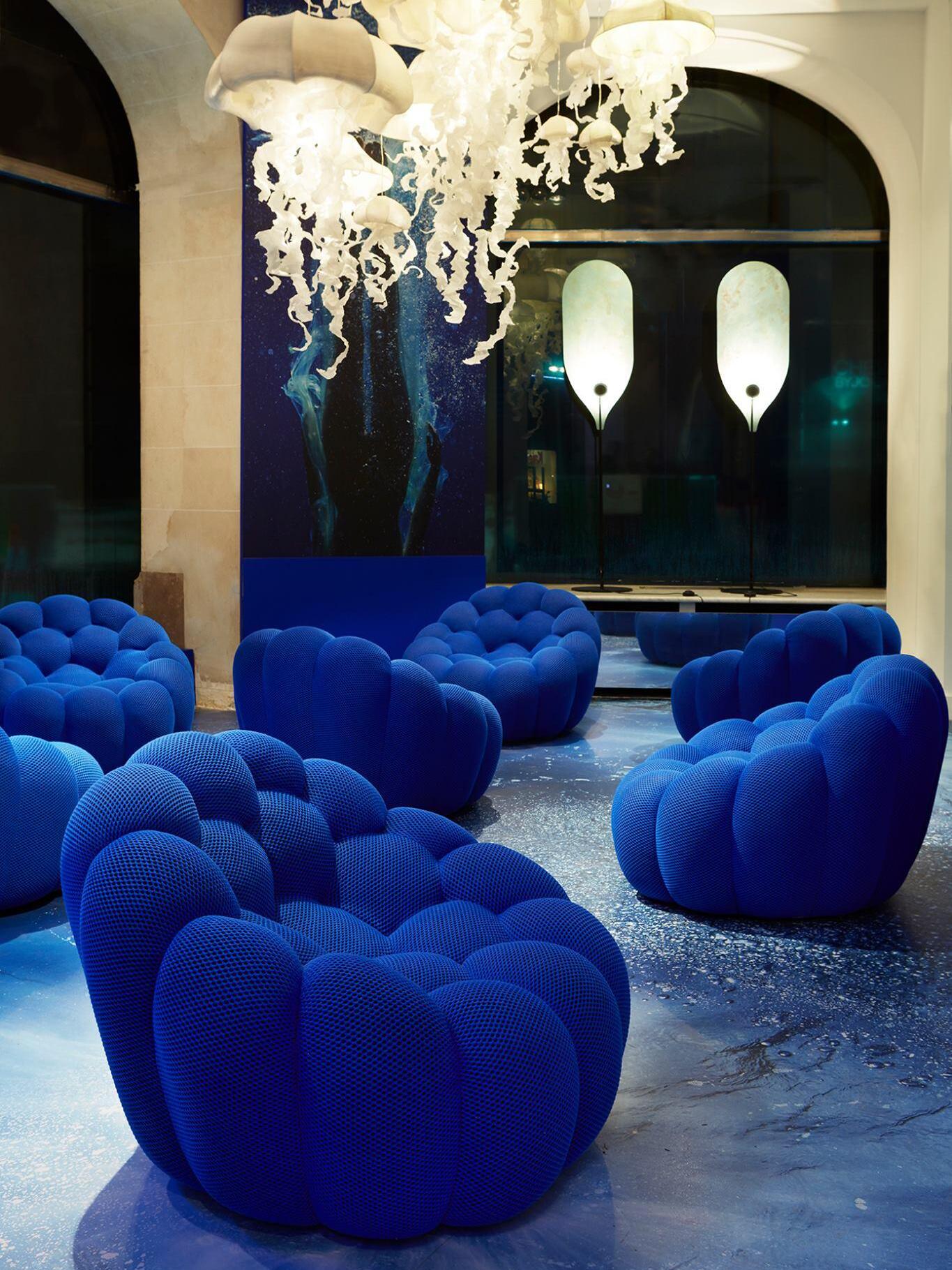 Decorative room with blue chairs, separate chandelier and panel lamps in background