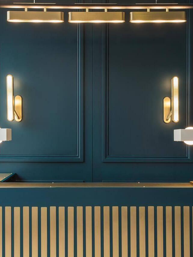 Two separate vertical grille wall lights on Dark Blue panels above a striped counter, with overhead horizontal lights