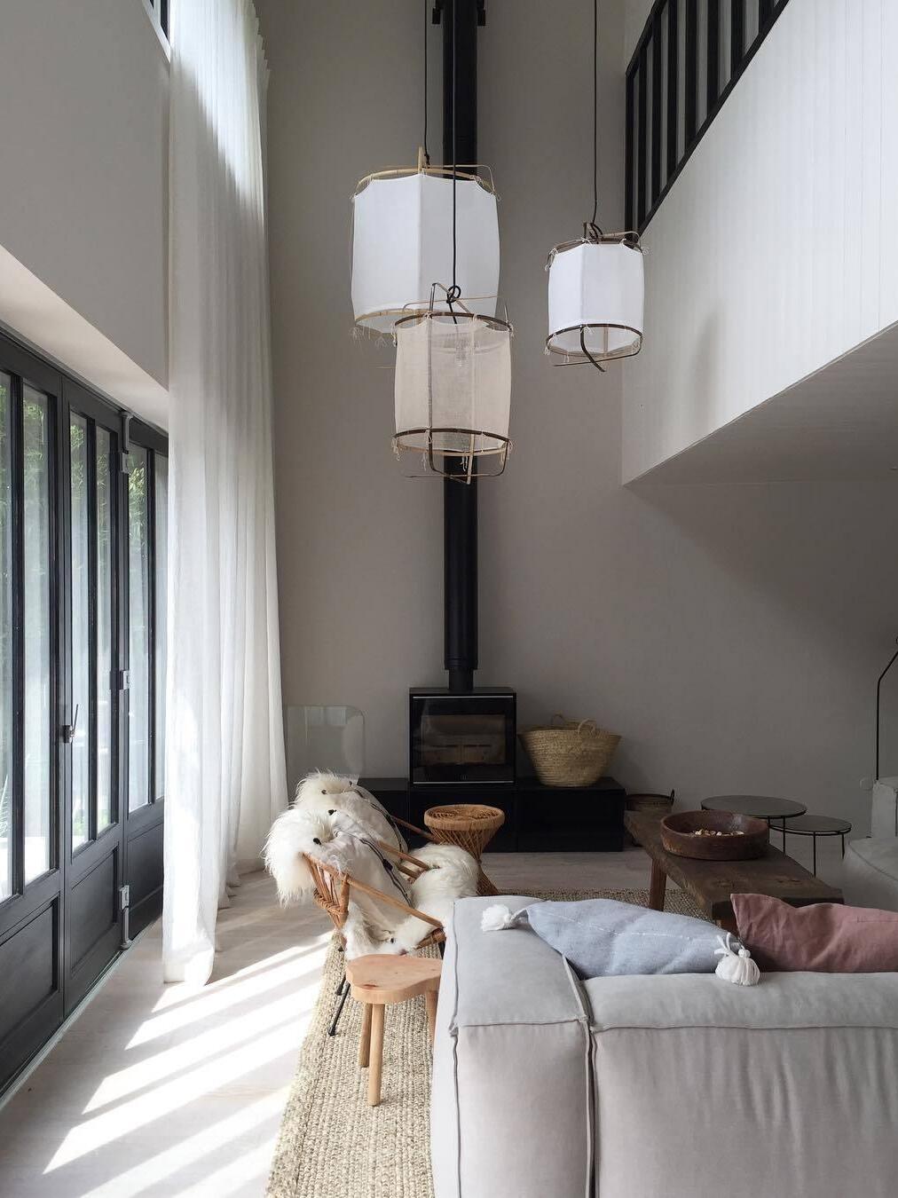 Three bamboo lantern pendants with different white sleeves at staggered heights in a double-height living room