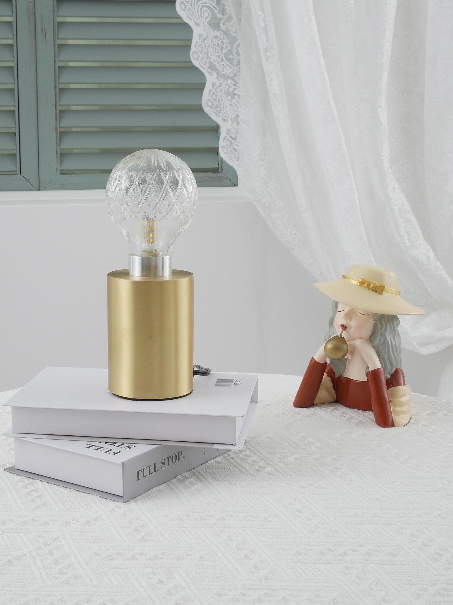 Clear globe lamp on white books beside curtain and shutters